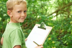 Boy Making Notes On School Nature Field Trip